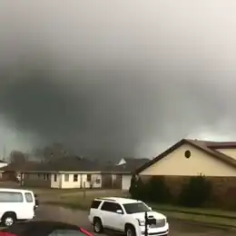 Image of tornado over the Michoud area of New Orleans with a fence and some trees visible in the foreground