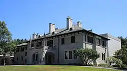 A two-and-a-half story stone building with slate roof and portico entrance.