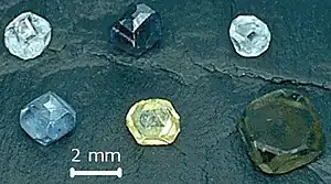 Six non-faceted diamond crystals of 2–3 mm (0.079–0.118 in) size; they are yellow, green-yellow, green-blue, light-blue, light-blue and dark blue.